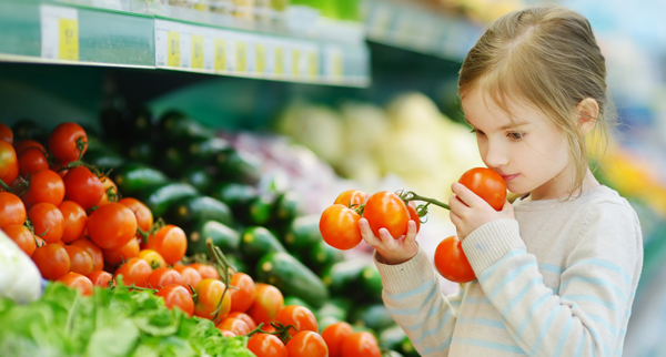 child in veggie section of grocery store
