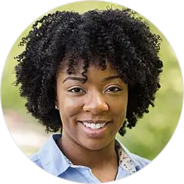 Susan with natural curly hair wearing a denim shirt in an outdoor setting 