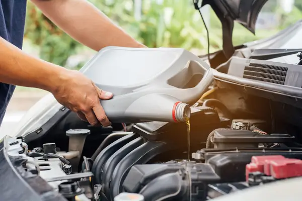 Car engine oil is being drained into a pan during the oil change process