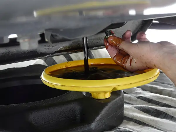 Close-up of a mechanic pouring fresh motor oil into a car engine during an oil change