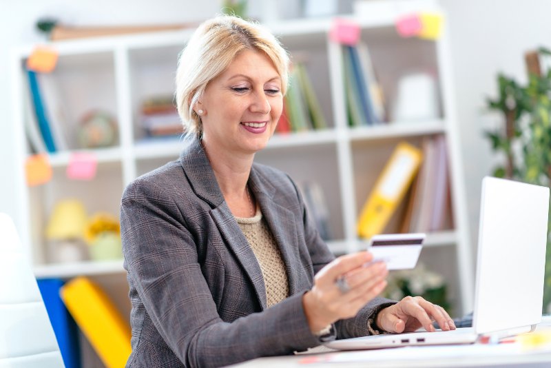 A woman smiling and looking at a credit card by Century Support Services