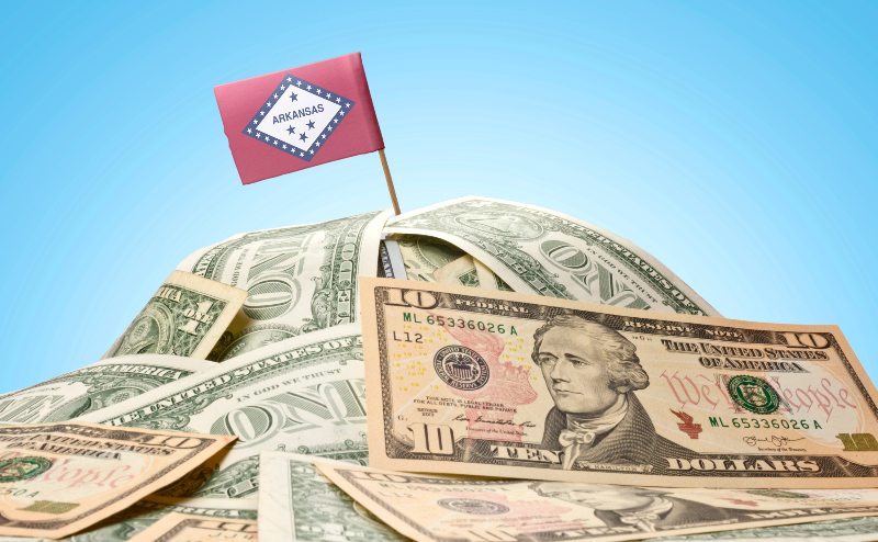 The flag of Arkansas sitting in a pile of money by Century Support Services