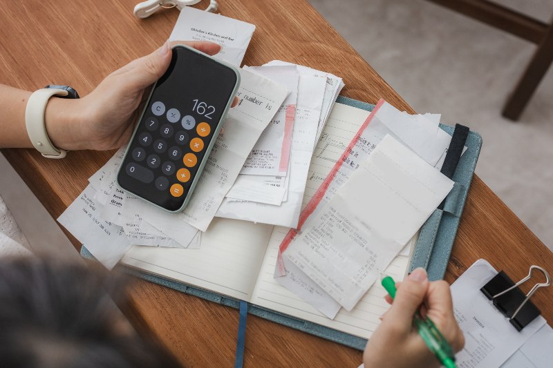 A close-up of a woman budgeting with receipts and a calculator by Century Support Services