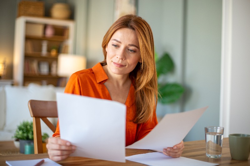 A woman smiling, reading about debt settlement by Century Support Services