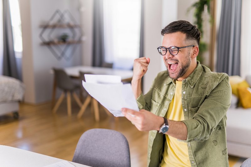 A man looking at papers and getting excited about debt settlement by Century Support Services