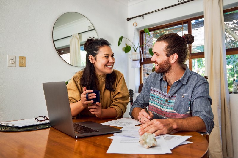 A happy couple smiling at each other and looking through the debt resolution process by Century Support Services