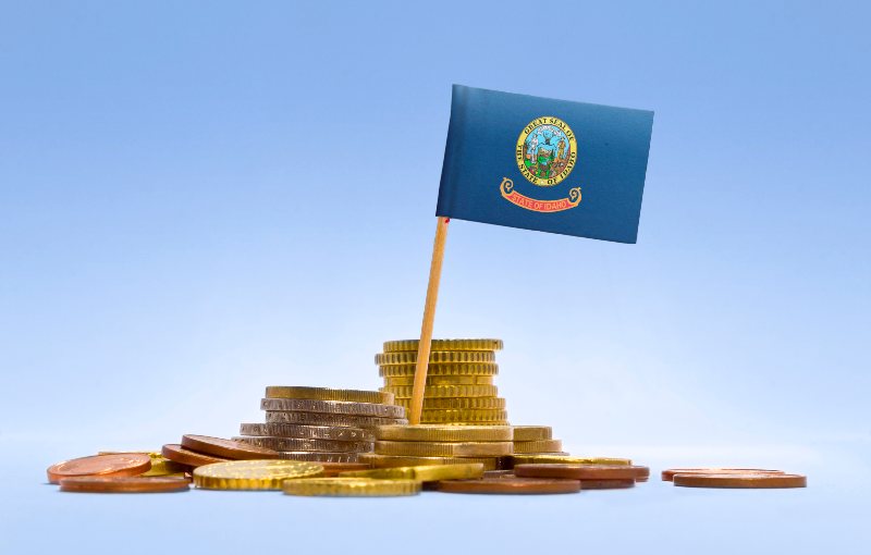 Flag of Idaho in a mixed stack of european coins and a blue background.(series)