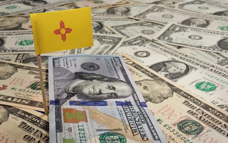 A New Mexico flag sitting on various bank notes by Century Support Services
