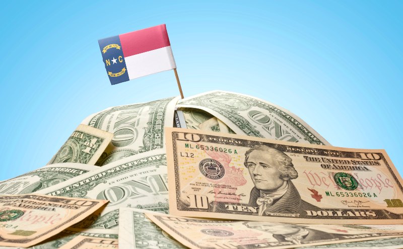 A North Carolina flag sticking out of a pile of money