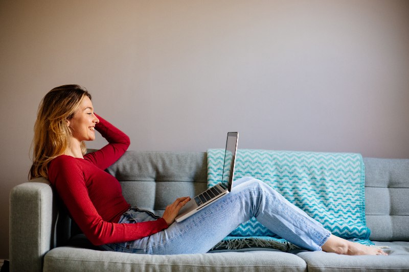 A woman smiling while looking at her payday loan debt relief on her laptop by Century Support Services