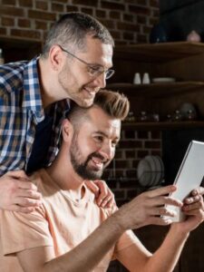 Two people looking at a tablet together in a cozy indoor setting with shelves behind them 