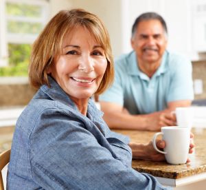 Two people sitting in a bright kitchen, one holding a white coffee mug at the counter