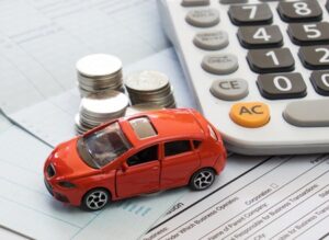 Car with coins, documents, and a calculator representing car finance or costs.