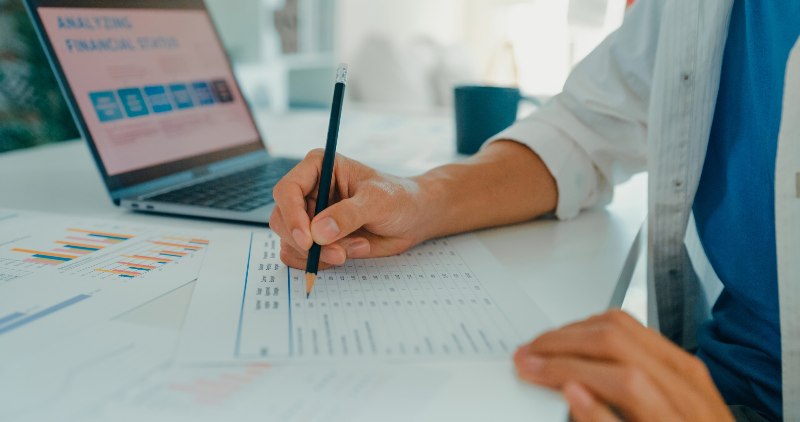 A person working on financial planning with paper and a laptop by Century Support Services