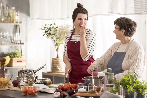 Two people cooking together in a kitchen, chopping vegetables and stirring a pot