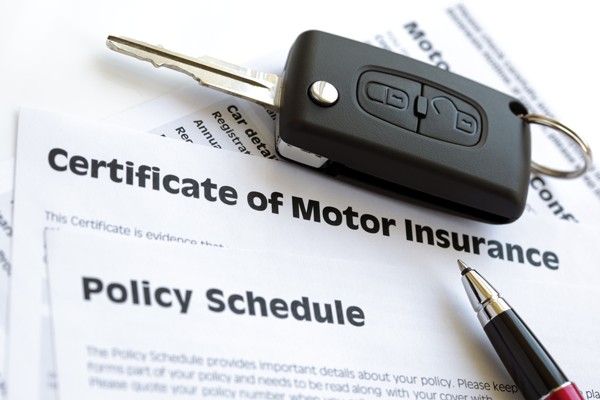 Car key on motor insurance documents with a pen beside the policy paperwork