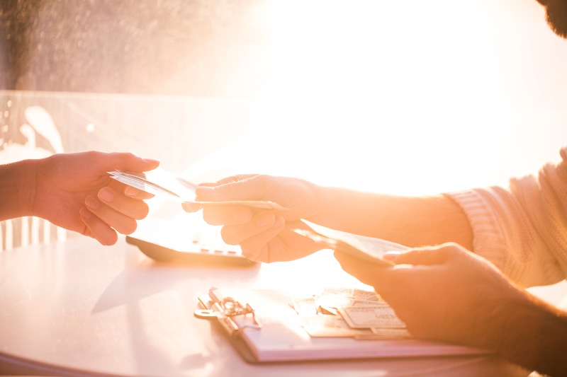 Someone handing someone else money with a notepad and calculator nearby by Century Support Services