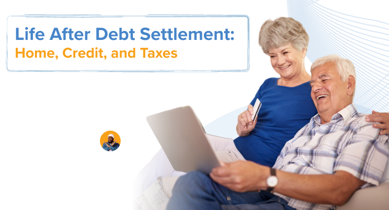 A couple sitting together on a couch, with the man holding a laptop on his lap, while the woman sits close with a credit card in her hand, as they look at the screen.